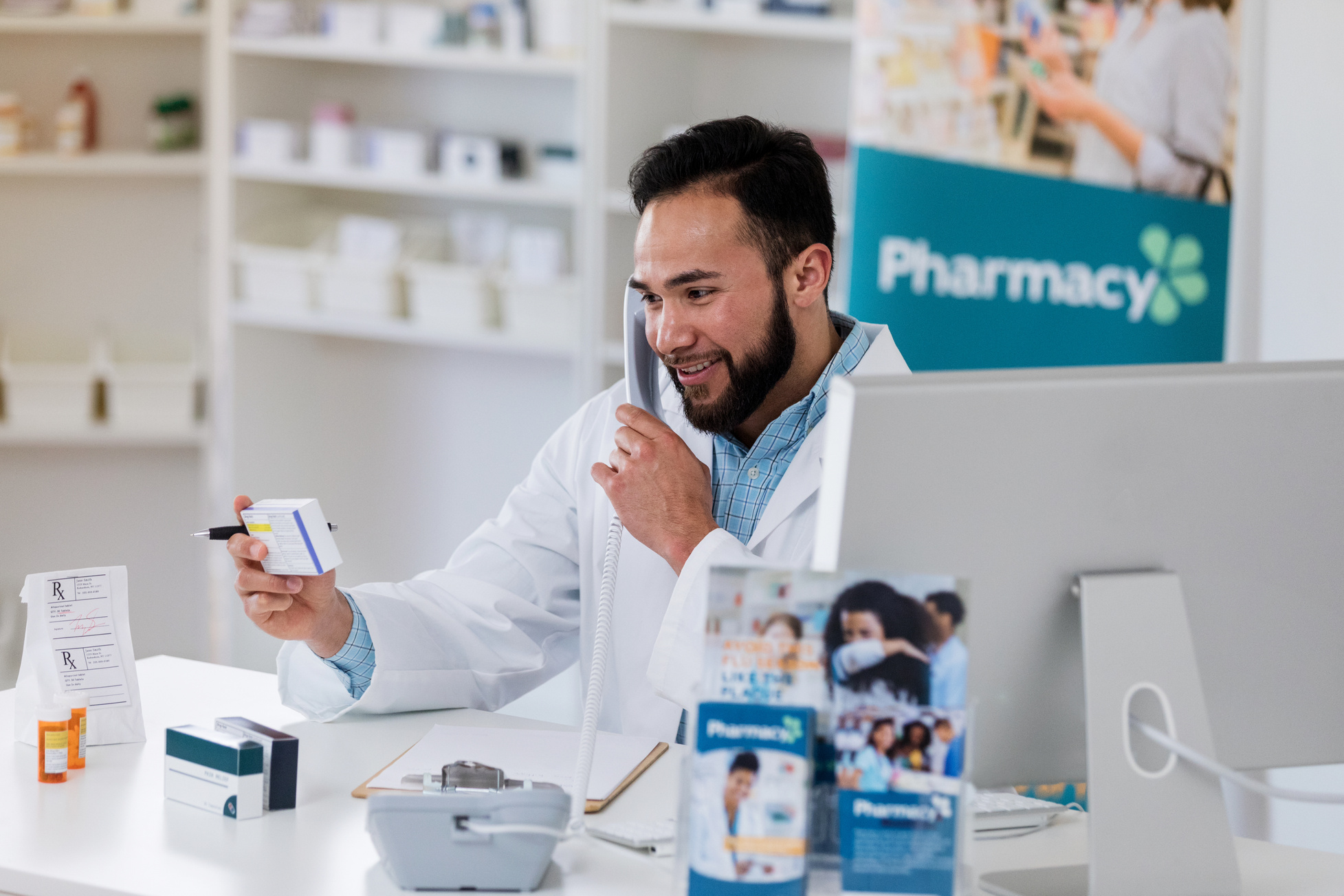 Male pharmacist uses pharmacy telephone